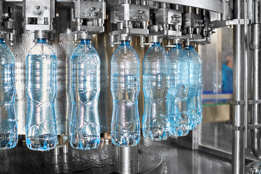 Water bottles being filled in a production line with machinery.