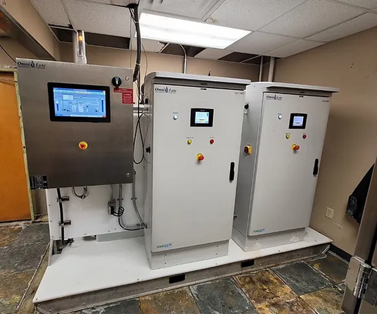 Industrial control panels with digital screens and buttons in a facility setting.