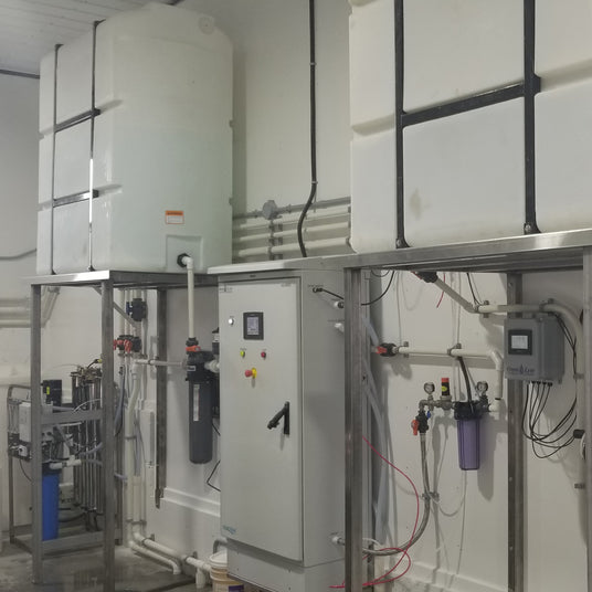Industrial water treatment setup with storage tanks and control panels.