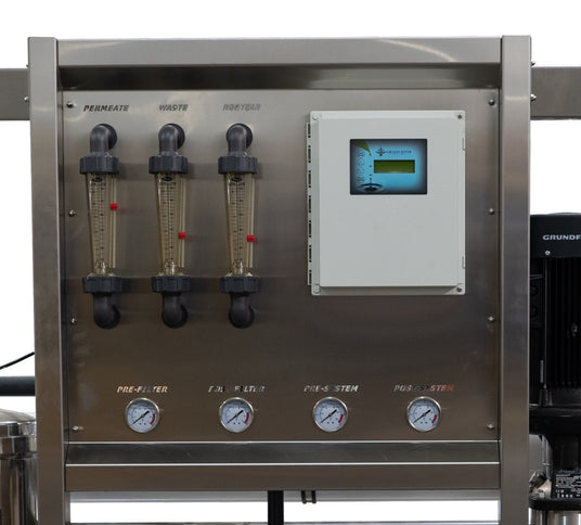 A metallic control panel with transparent tubes for permeate, waste, and recycle, featuring gauges and a digital display for monitoring systems.