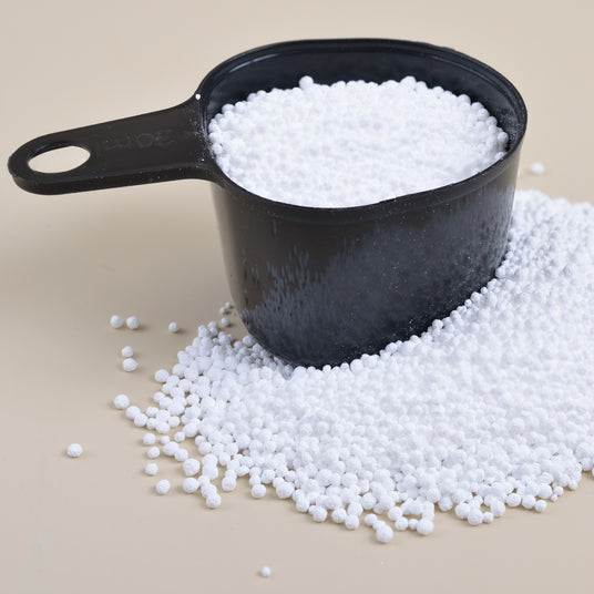 White granules spilling from a black measuring cup.