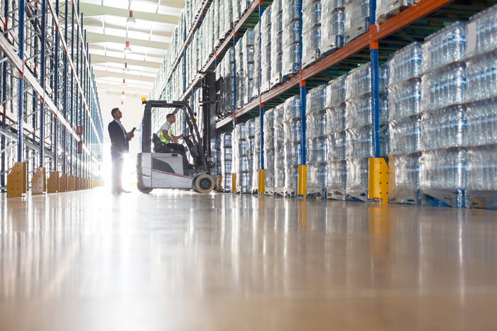 Warehouse interior with a forklift and stacked water bottles.