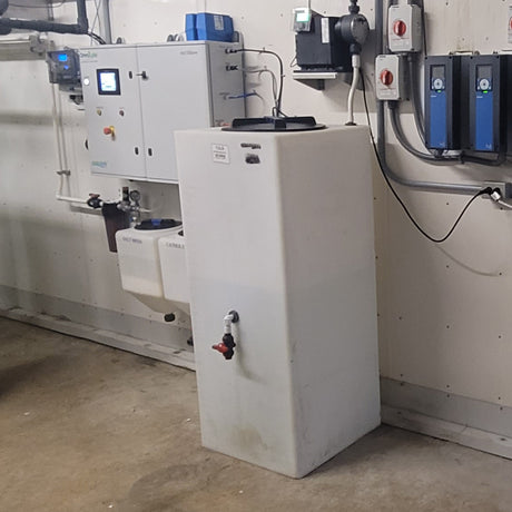 Industrial equipment setup with a control panel and a large white tank.