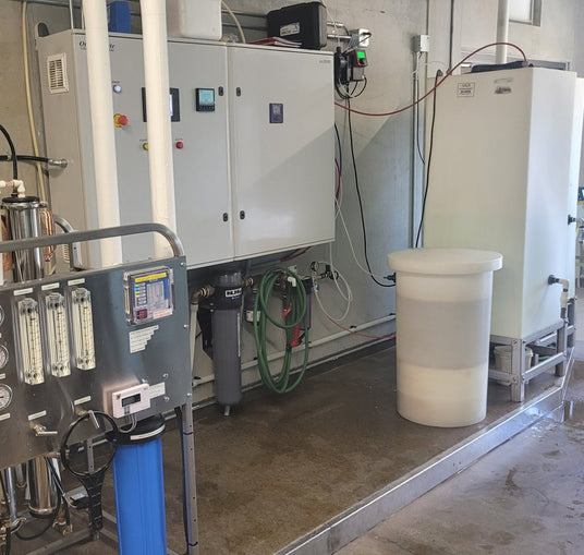 Industrial water treatment equipment with a control panel, filters, and a storage tank.