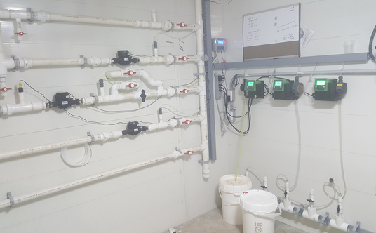 Photo of a plumbing installation with various pipes, valves, and electronic meters mounted on a wall.