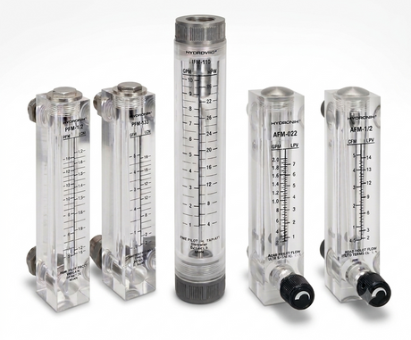 Five clear plastic flow meters with black measurement markings and black fittings, arranged on a light gray studio background. The set includes different flow meter models, with one central taller meter and four shorter side meters.
