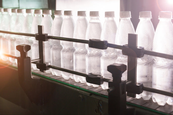 Row of clear plastic water bottles on a conveyor belt.