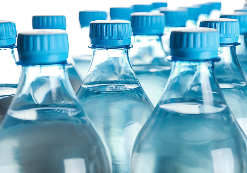 A collection of clear plastic water bottles with blue caps.