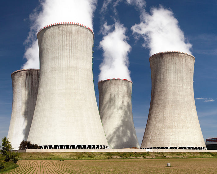Cooling towers releasing steam against a blue sky.
