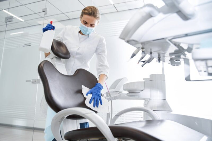 Dental professional cleaning a chair in a clinic.