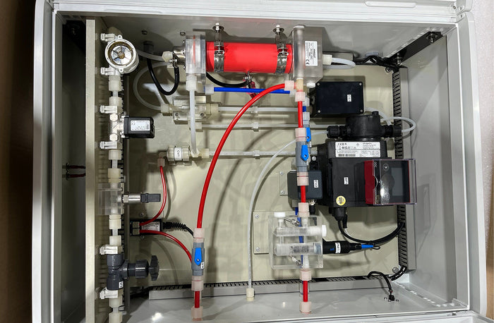 Interior view of a mechanical device or apparatus with pipes, valves, and a red component.