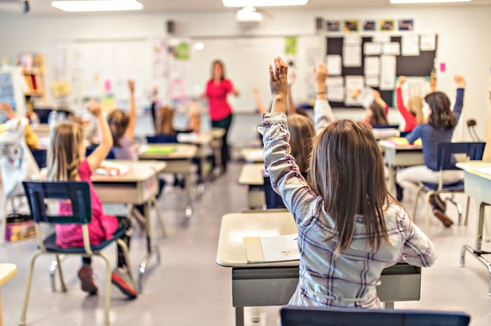 Classroom scene with students raising their hands to answer a question.